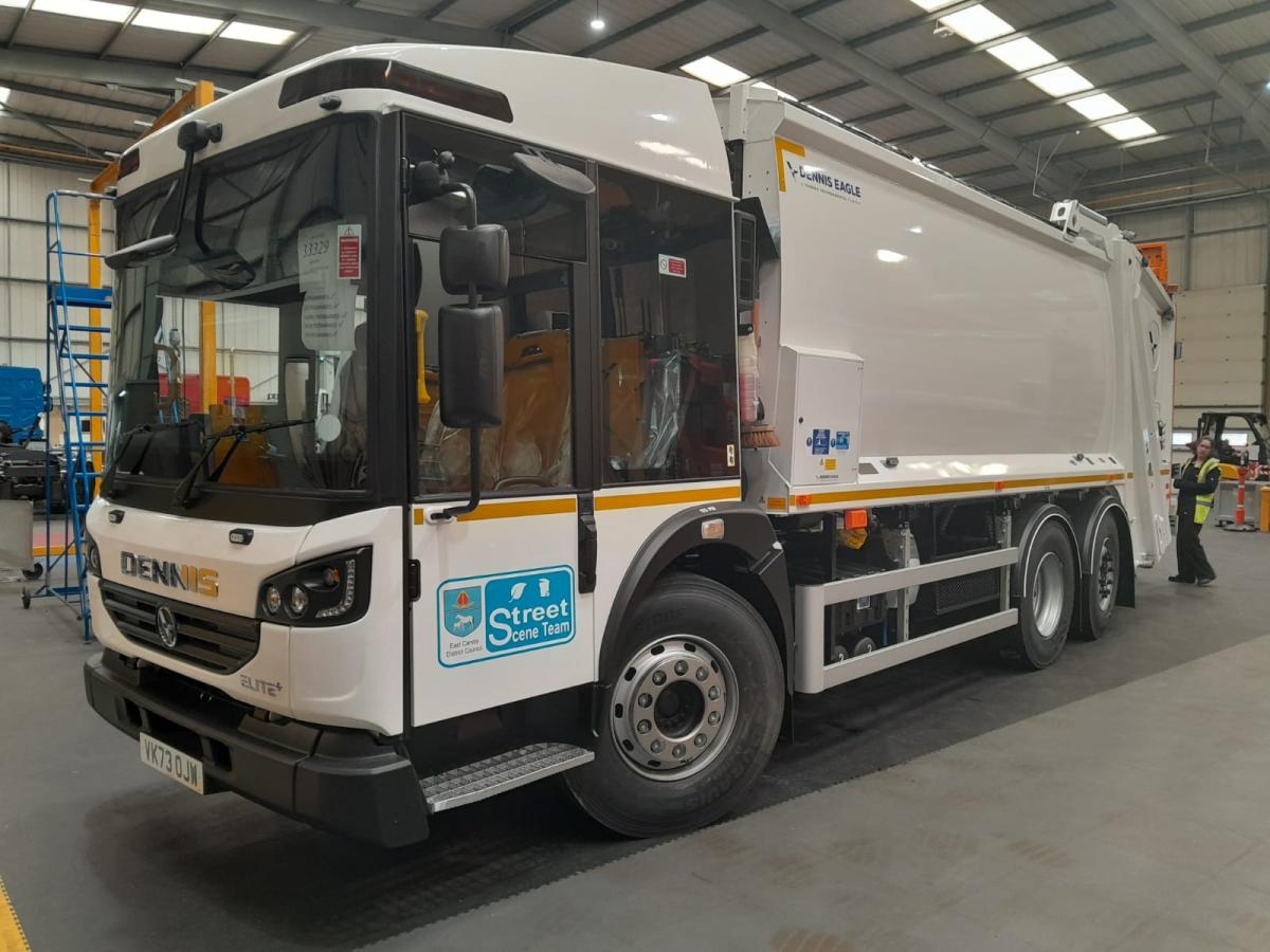 A new white refuse lorry in a storage shed