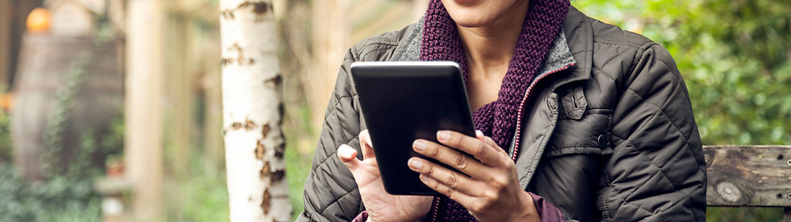 woman sitting in a garden using a digital tablet 